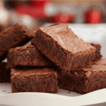 Delicious fudgy brownies with a crackly top, cut into squares and stacked on a white plate. The perfect homemade treat for chocolate lovers.